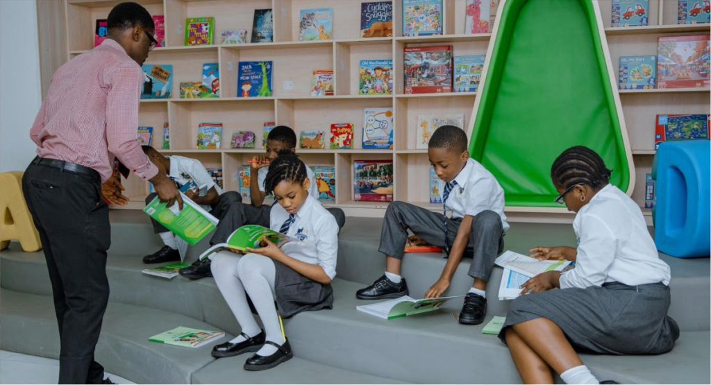 Primary students being instructed by a teacher in Jewels Leading Lights international library